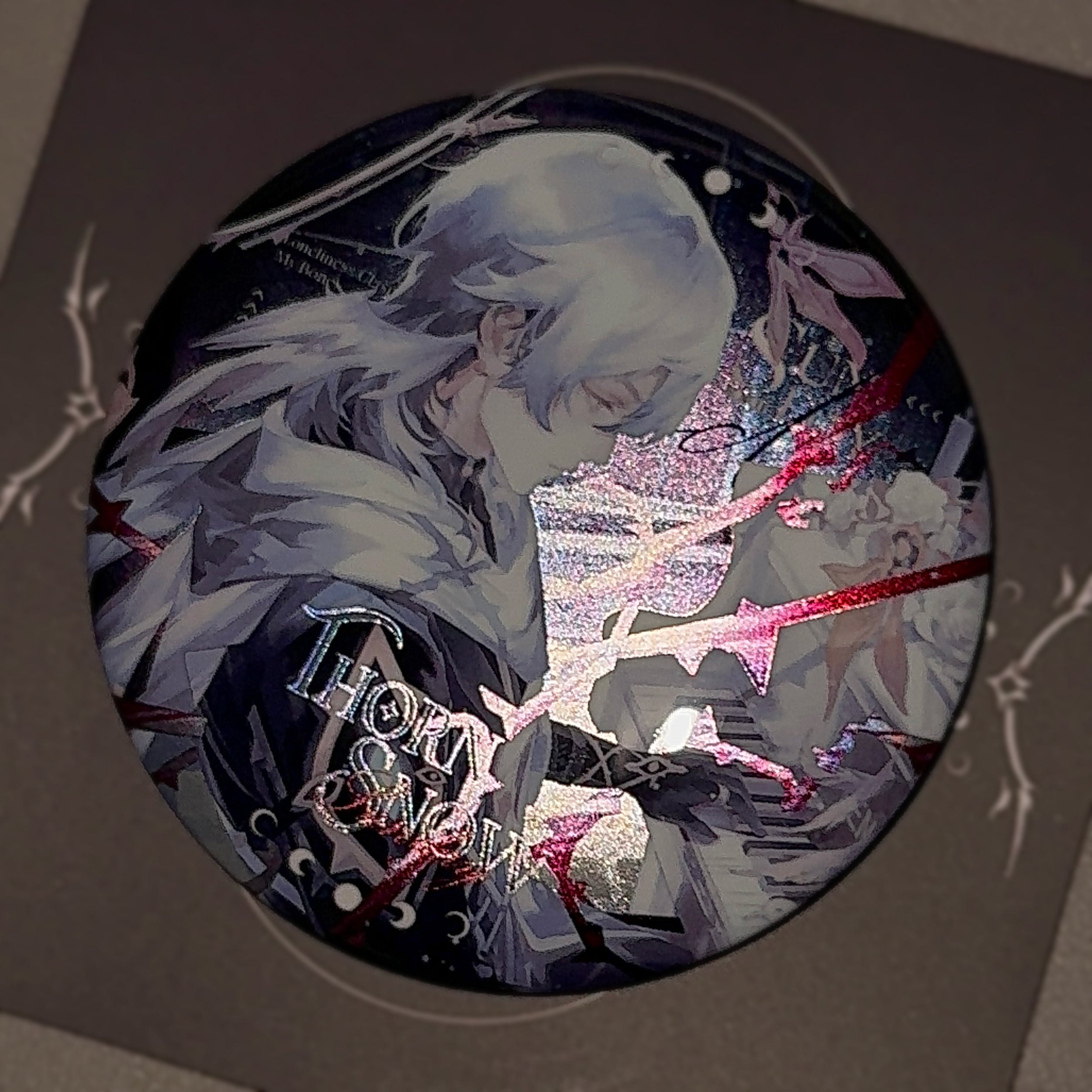 Angled view of Sunday 75mm badge showing glossy finish and vibrant double-holographic reflection under light, winter-themed HSR merch.