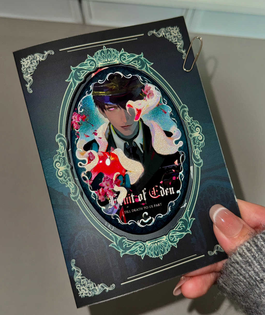 Physical display of Caleb Forbidden Apple oval button badge with matching backing card by AO Treehouse.