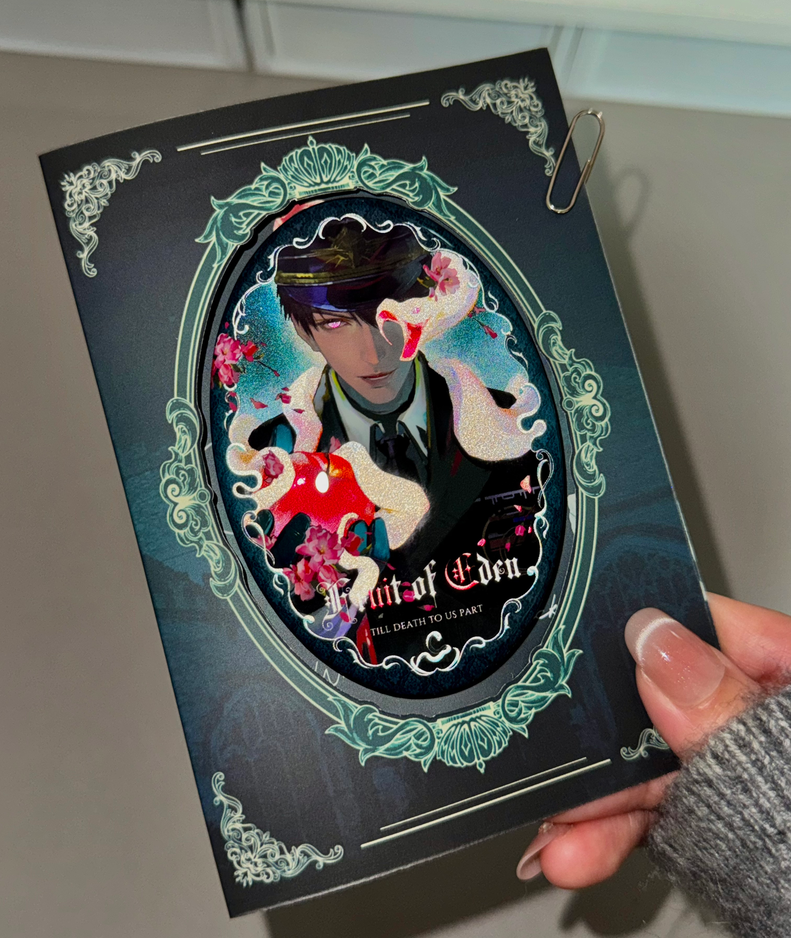 Physical display of Caleb Forbidden Apple oval button badge with matching backing card by AO Treehouse.